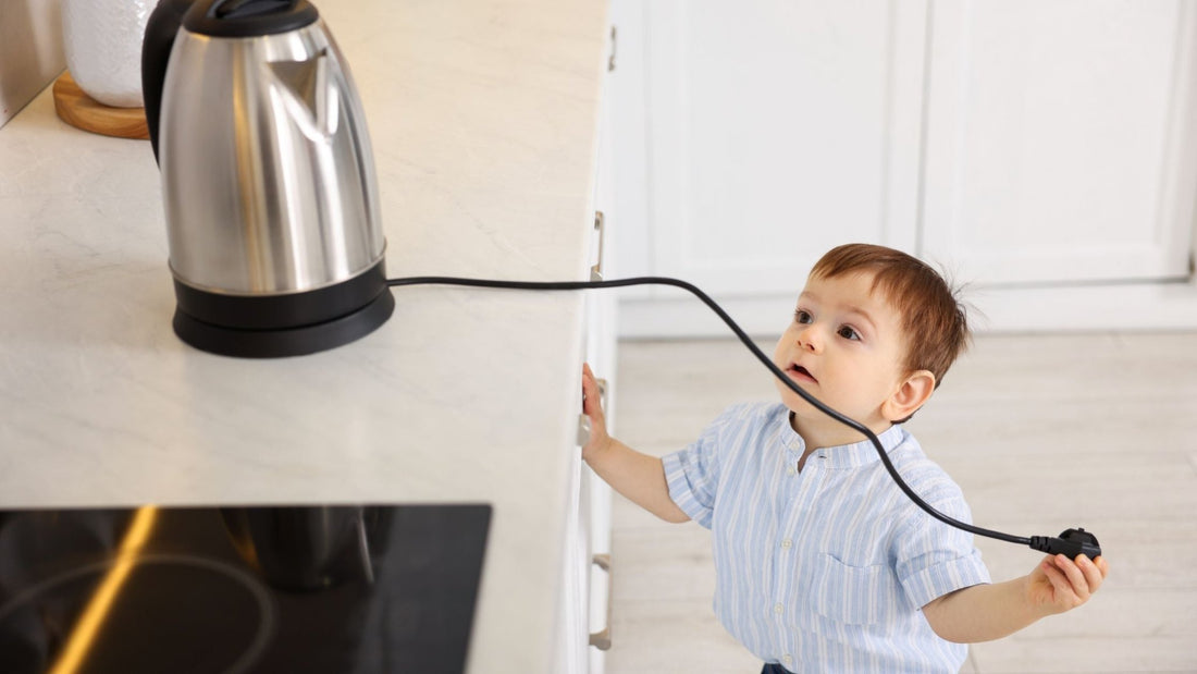 YOung child at risk of burn from pulling a kitchen jug by the power cord. Blog on burn prevention for kids in the home.