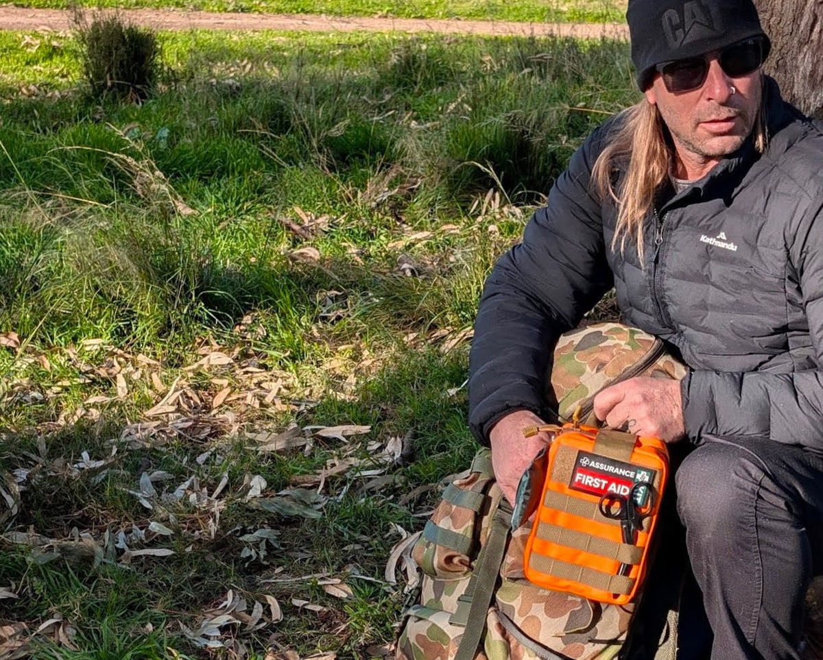 Man packing a snake bite kit into a back pack